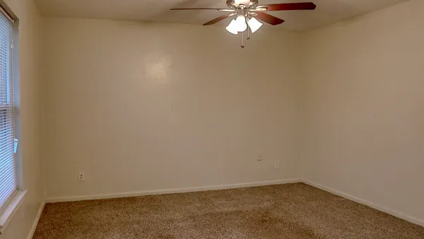 an empty room with a chandelier fan