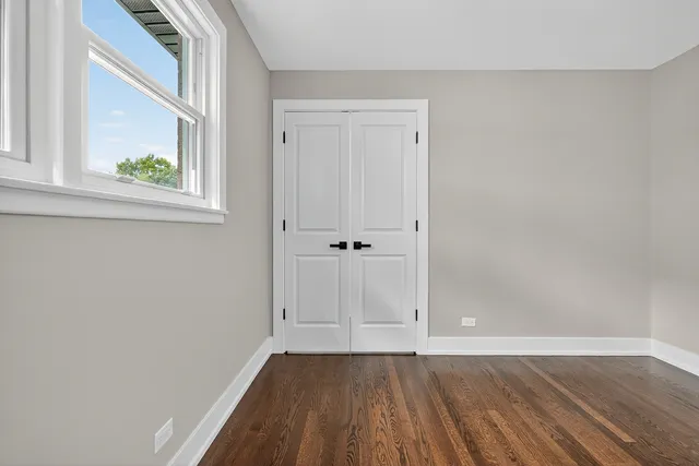 a view of an empty room with wooden floor and window