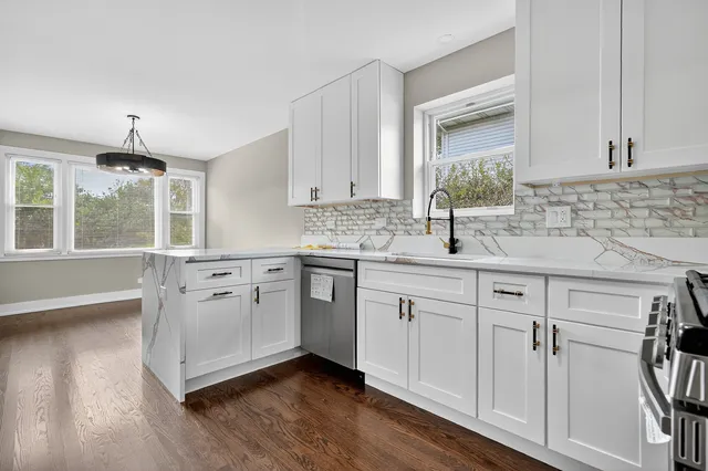 a kitchen with stainless steel appliances granite countertop a sink cabinets and wooden floor