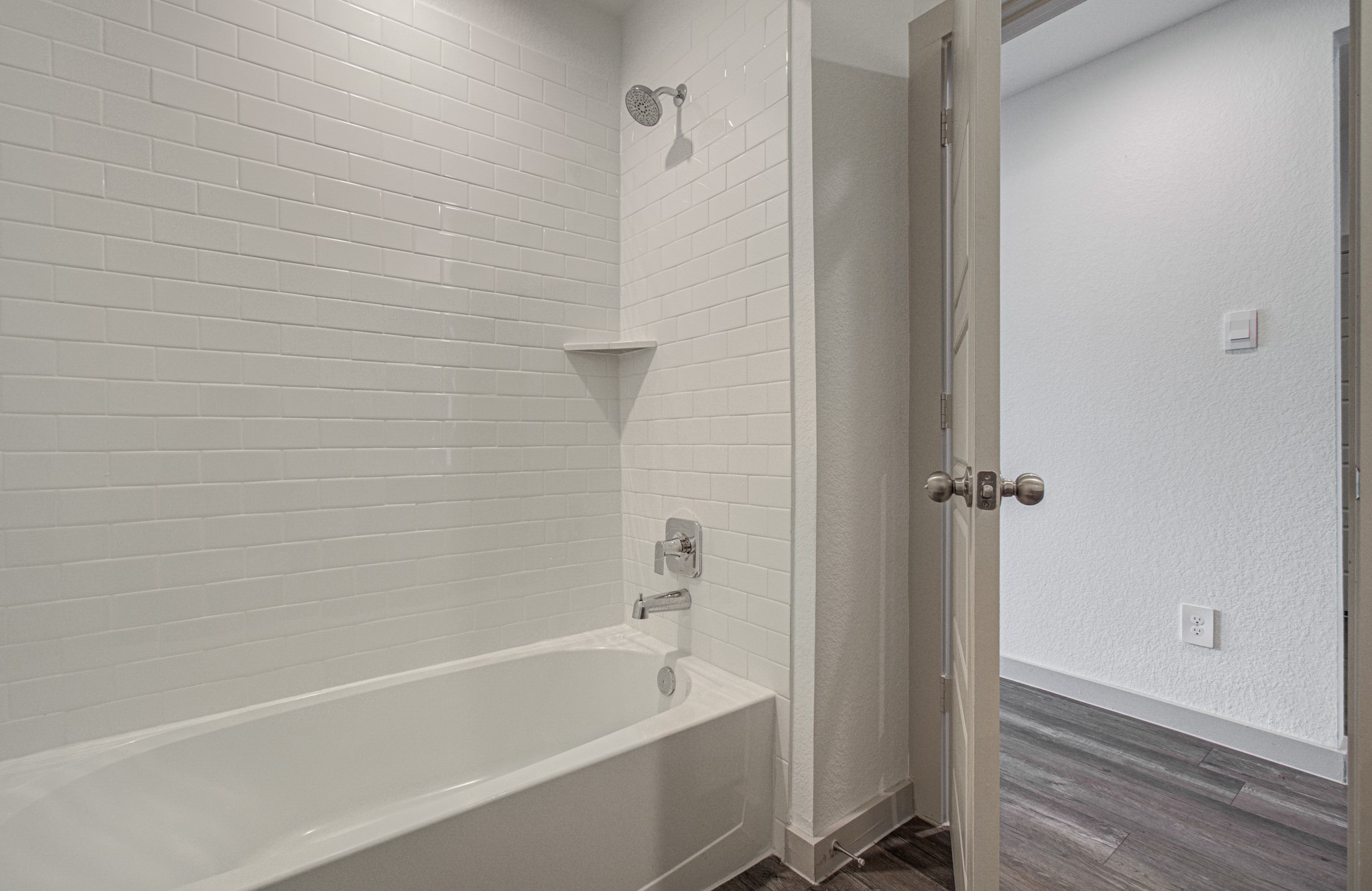 7903 Wrangler Shack Lane Rosharon, TX 77583 - Photo 11 of 29 This bright bathroom showcases sleek fixtures and a modern white subway tile shower-tub combo, with elegant double doors opening to a room featuring rich dark wood flooring.