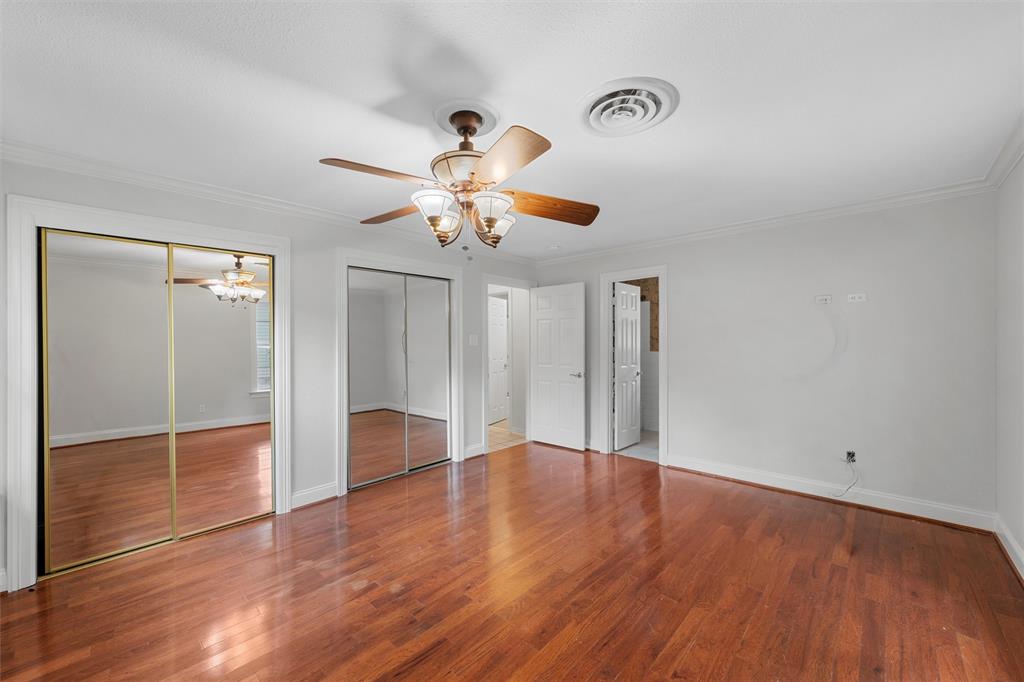 2131 Mountainview Drive Waco, TX 76710 - Photo 16 of 27 Unfurnished bedroom with multiple closets, crown molding, wood finished floors, a ceiling fan, and a chandelier