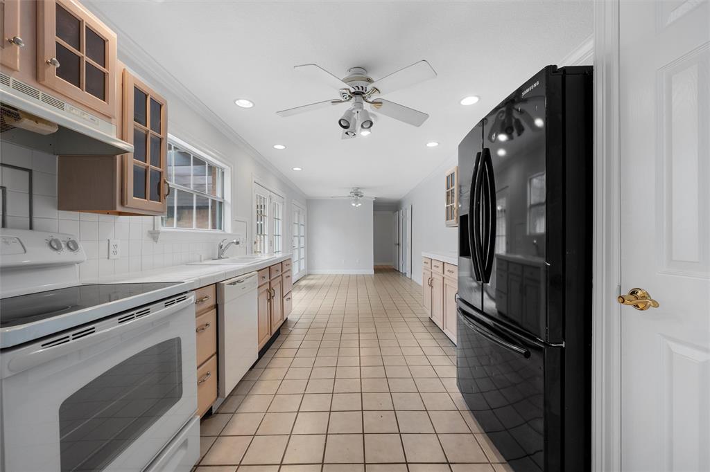 2131 Mountainview Drive Waco, TX 76710 - Photo 8 of 27 Kitchen with glass insert cabinets, white appliances, crown molding, light tile patterned floors, and tasteful backsplash
