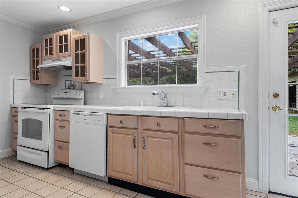 2131 Mountainview Drive Waco, TX 76710 - Photo 9 of 27 Kitchen featuring tile counters, white appliances, light brown cabinetry, light tile patterned floors, and backsplash