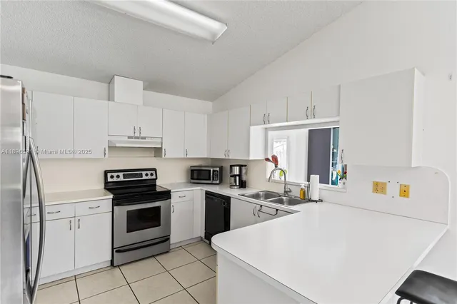 a kitchen with granite countertop a sink stove and white cabinets