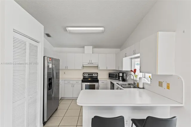 a large white kitchen with stainless steel appliances a refrigerator a stove a microwave and a refrigerator