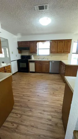 a view of a kitchen with kitchen island a sink dishwasher stove and oven with wooden floor