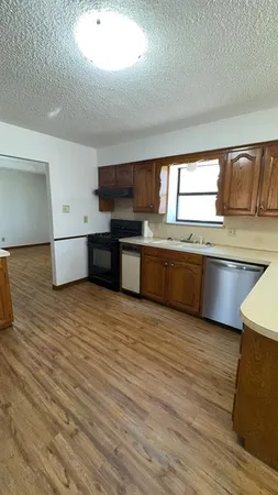 a large kitchen with stainless steel appliances granite countertop a sink dishwasher stove and wooden floor
