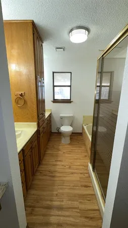 an empty room with wooden floor and a bathroom view