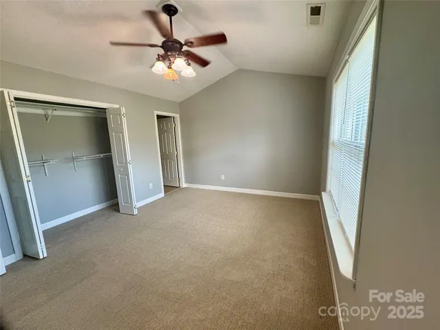 an empty room with closet and a ceiling fan