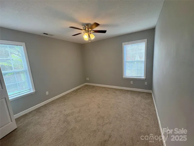 an empty room with windows and fan