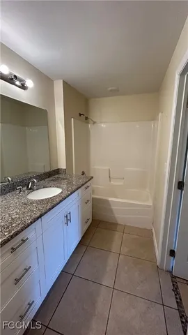a bathroom with a granite countertop sink a mirror and a bathtub