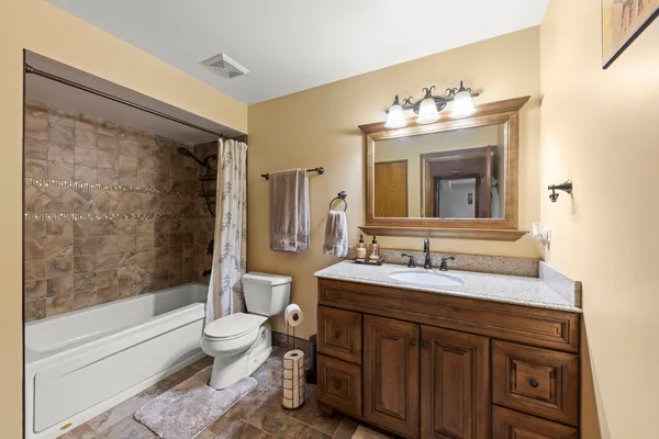 a bathroom with a sink vanity mirror bathtub and toilet