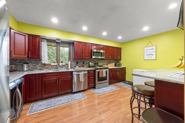 a kitchen with stainless steel appliances kitchen island granite countertop wooden cabinets a dining table and chairs