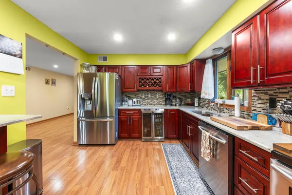 a large kitchen with stainless steel appliances wooden cabinets a stove a sink and a center island