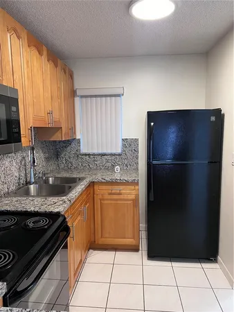 a kitchen with granite countertop a refrigerator and a stove top oven