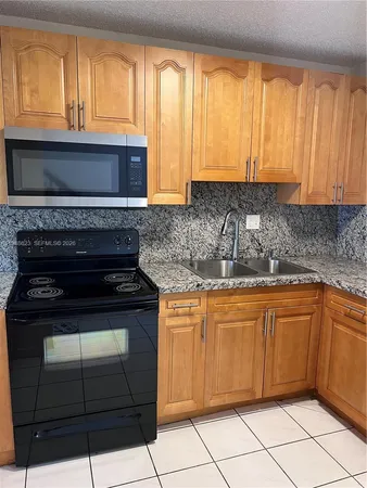 a kitchen with granite countertop a stove a sink and a microwave