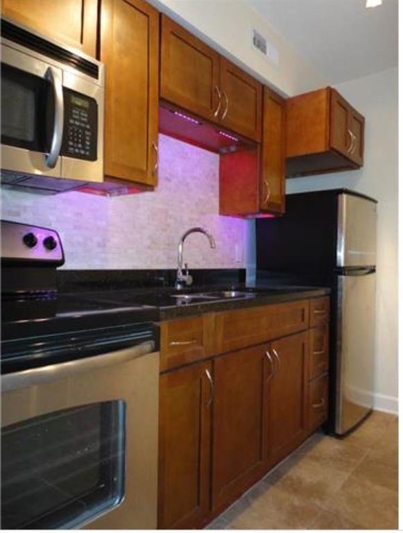2020 South Congress Avenue, Unit 1313 Austin, TX 78704 - Photo 5 of 11 a kitchen with stainless steel appliances granite countertop a stove a microwave oven and a sink with granite countertops