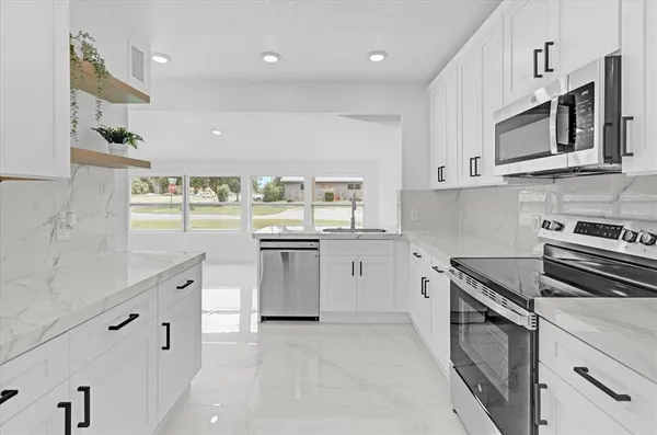 a kitchen with white cabinets and appliances