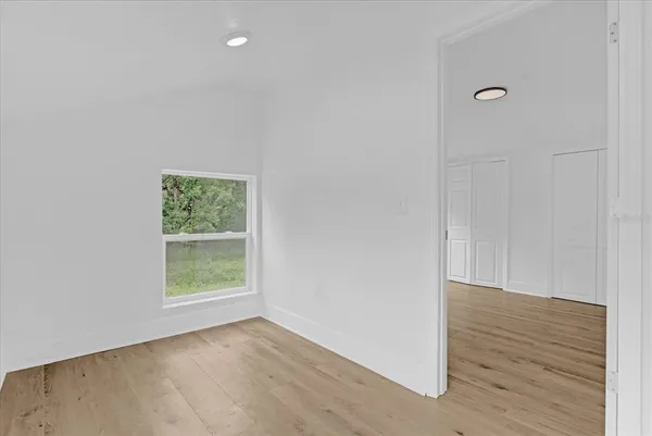 a view of an empty room with wooden floor and a window