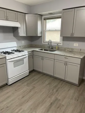a kitchen with granite countertop white cabinets sink and stainless steel appliances
