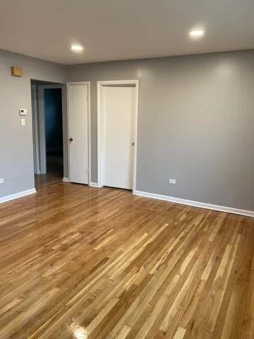 an empty room with wooden floor and bathroom view