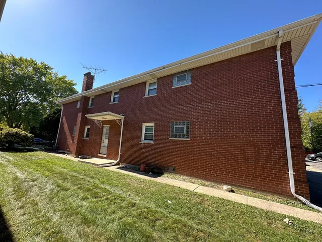 a backyard of a house with large trees and a wooden fence