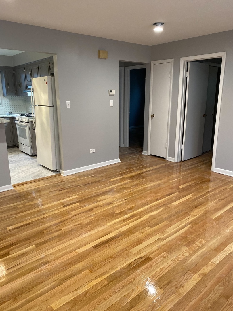 2290 182nd Place Lansing, IL 60438 - Photo 9 of 23 an empty room with wooden floor and a kitchen view