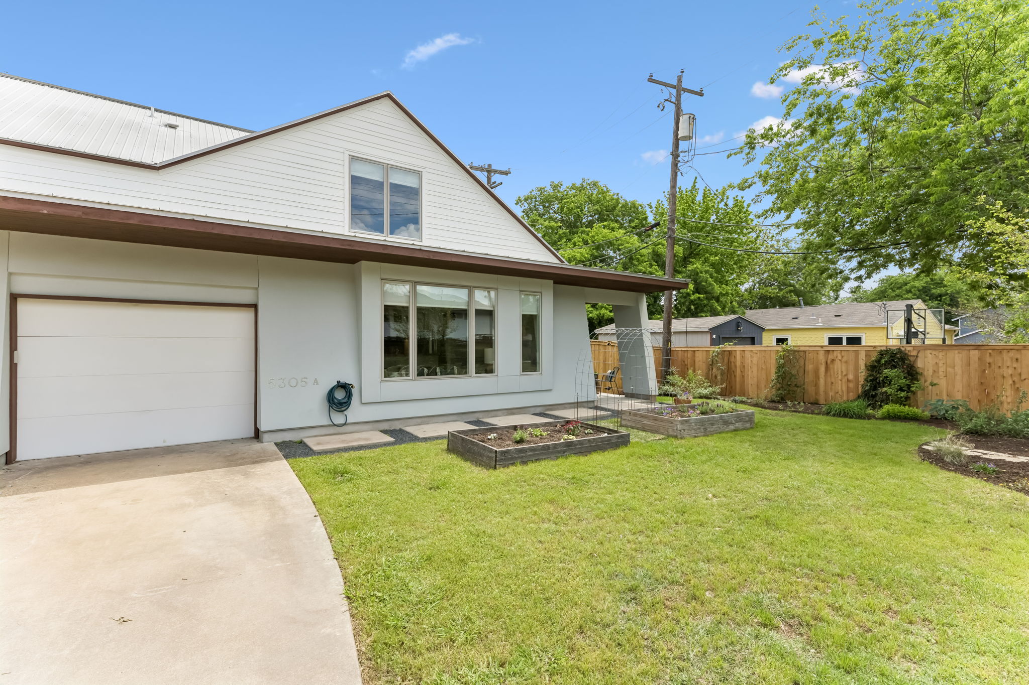 5305 Guadalupe Street, Unit A Austin, TX 78751 - Photo 2 of 31 View of front facade featuring a garden, a patio area, concrete driveway, and a garage