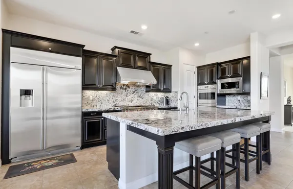 a kitchen with stainless steel appliances granite countertop a sink and a refrigerator