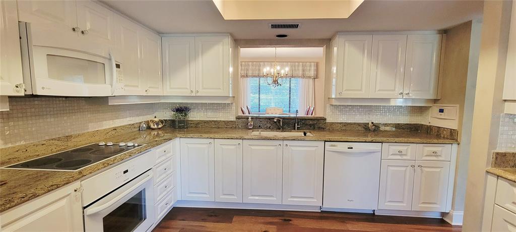 1004 Old Mill Pond Road Palm Harbor, FL 34683 - Photo 16 of 48 a kitchen with granite countertop white cabinets and white appliances