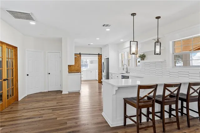 a open kitchen with stainless steel appliances granite countertop a table chairs stove and wooden floor