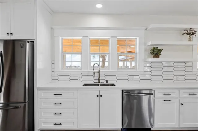 a kitchen with granite countertop a sink stainless steel appliances and cabinets