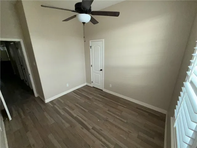 an empty room with wooden floor and fan