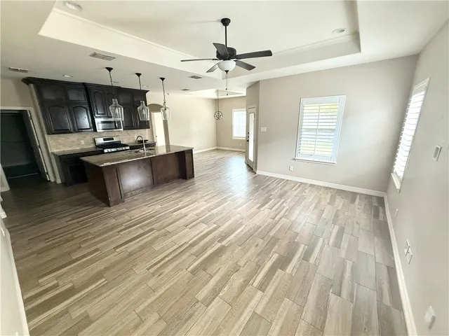 a large kitchen with cabinets a sink dishwasher a stove and a dining table with wooden floor