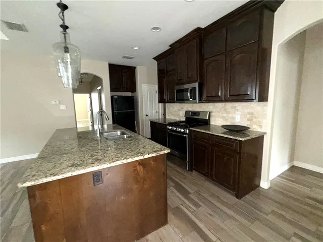 a kitchen with stainless steel appliances granite countertop a sink a stove and refrigerator