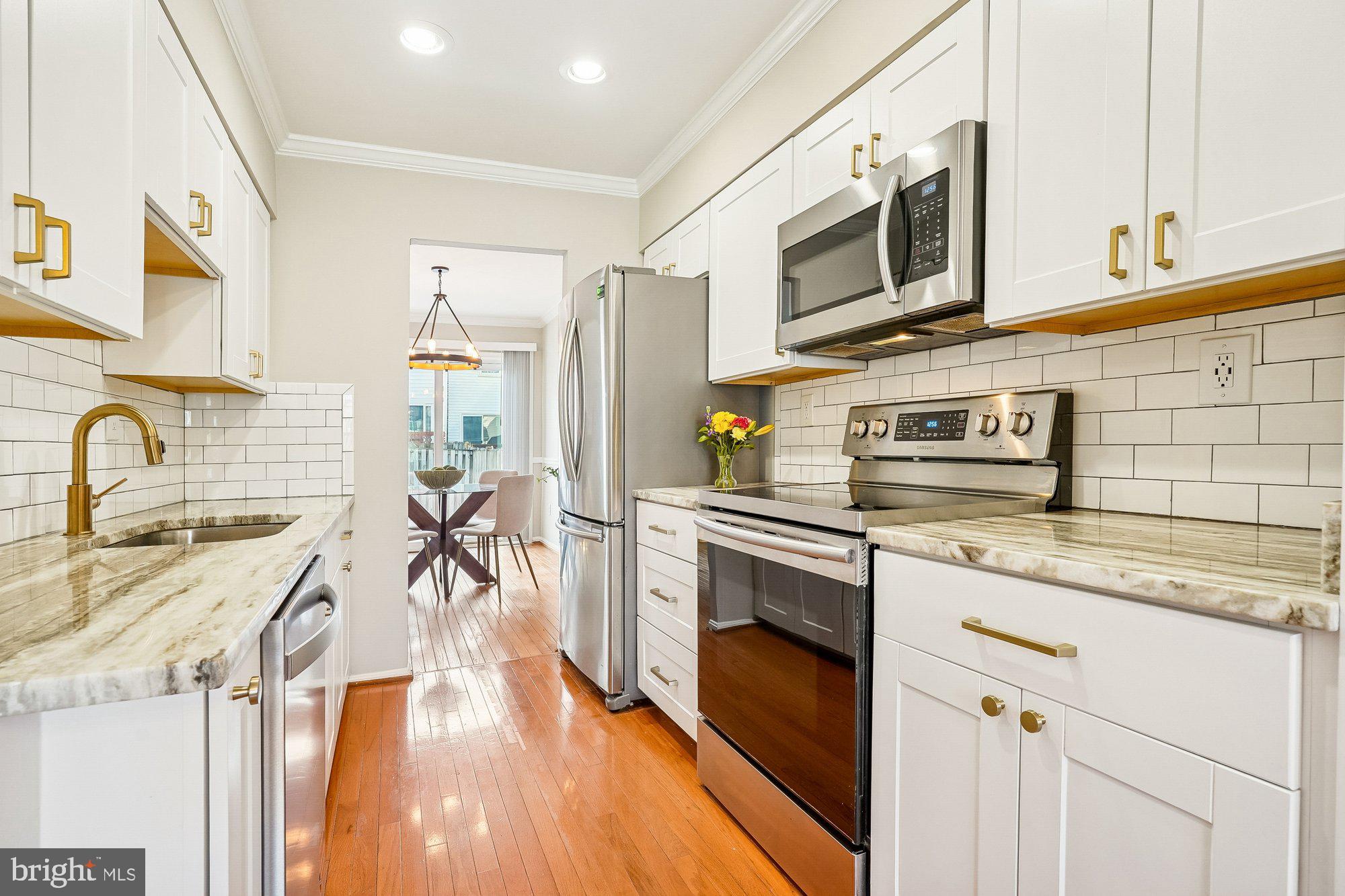 8826 Surveyors Place Springfield, VA 22152 - Photo 2 of 40 a kitchen with stainless steel appliances granite countertop a sink a stove a microwave oven a refrigerator with white cabinets and wooden floor