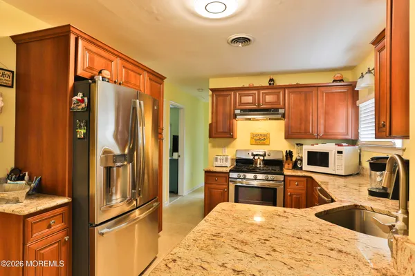 a kitchen with stainless steel appliances granite countertop a refrigerator a stove and a sink with wooden floor
