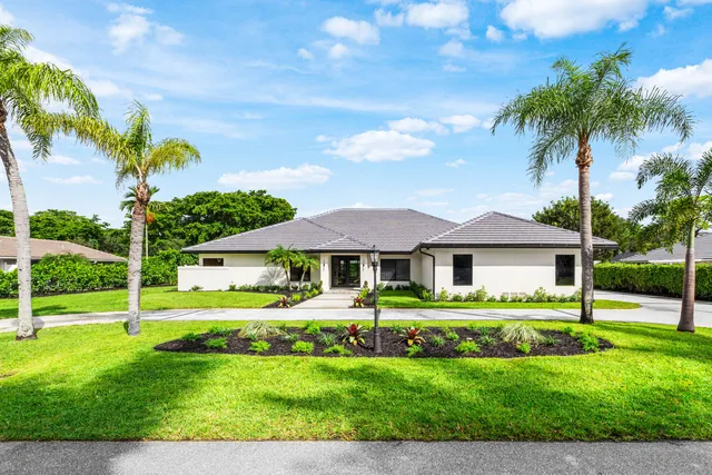 a view of a house with a big yard and palm trees