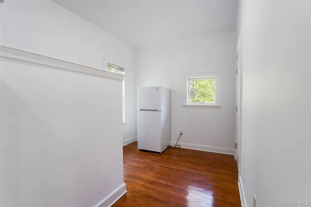 a view of empty room with wooden floor and window