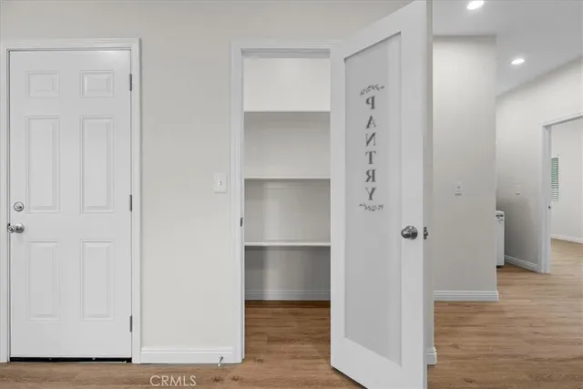 a view of an empty room with wooden floor and closet area