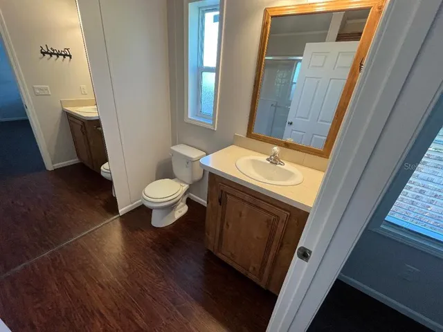 a bathroom with a sink a toilet a mirror and a window
