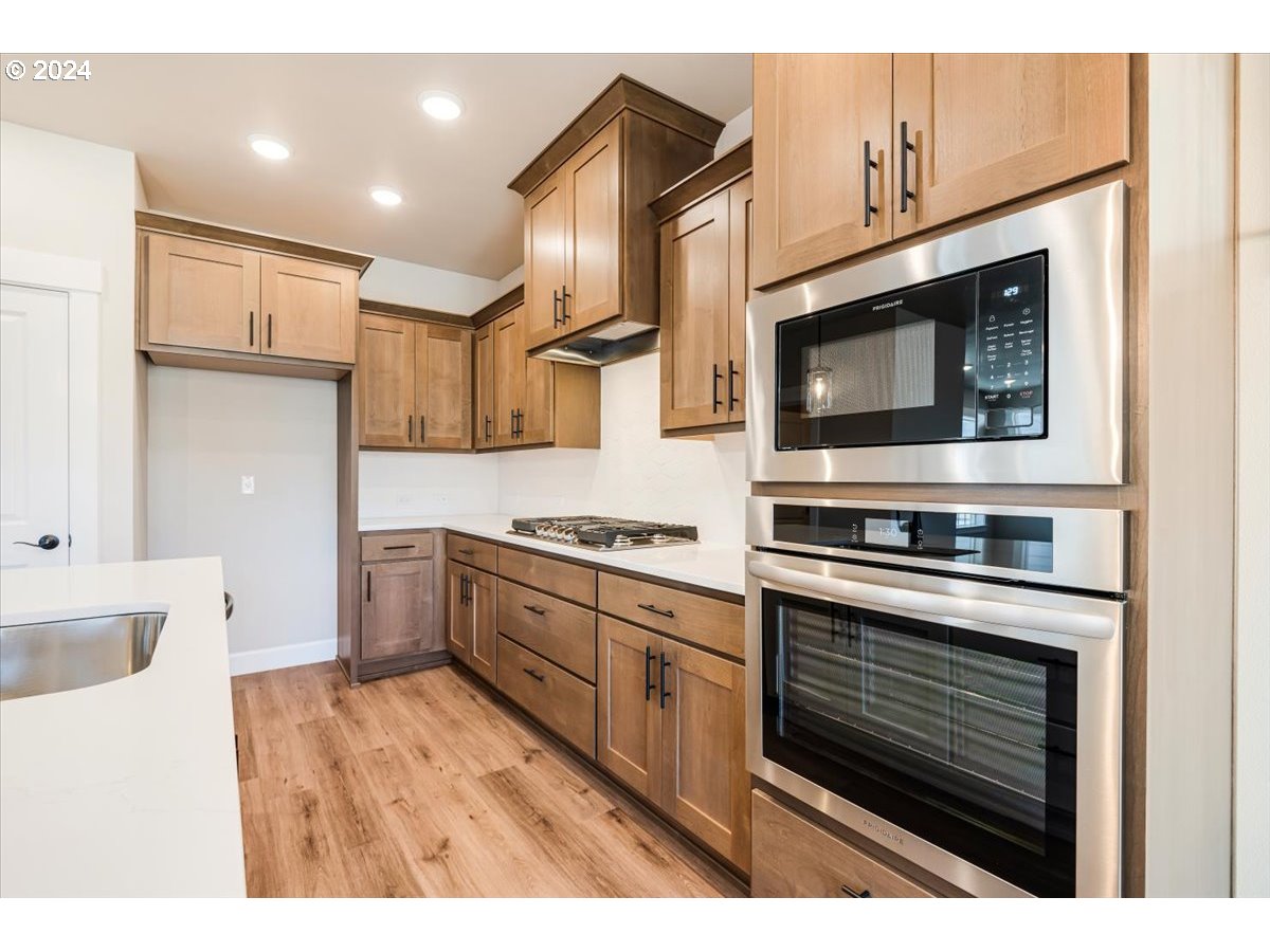 18050 Southwest Barrows Road Beaverton, OR 97007 - Photo 13 of 45 a kitchen with stainless steel appliances kitchen island granite countertop a stove top oven microwave and cabinets