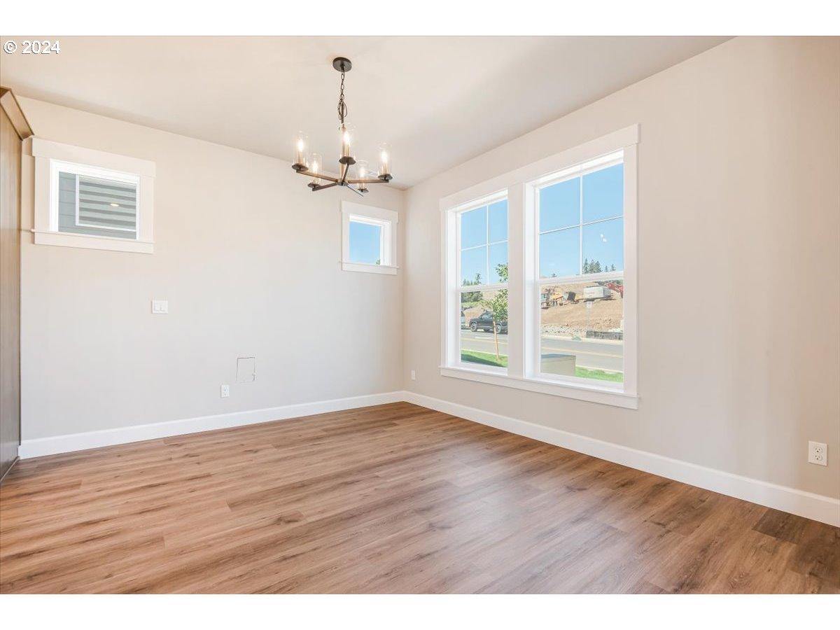 18050 Southwest Barrows Road Beaverton, OR 97007 - Photo 16 of 45 an empty room with wooden floor chandelier fan and windows