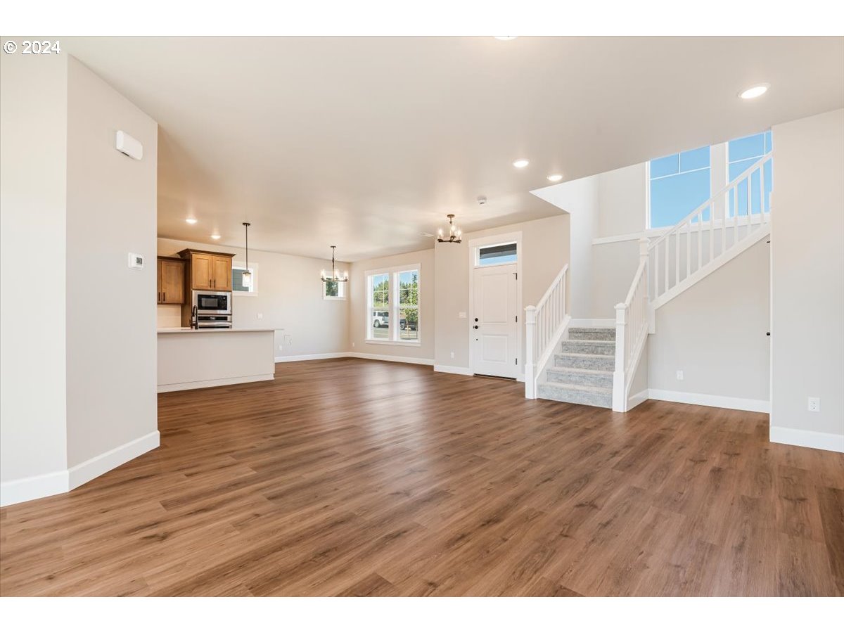 18050 Southwest Barrows Road Beaverton, OR 97007 - Photo 9 of 45 a view of an empty room with wooden floor and a kitchen