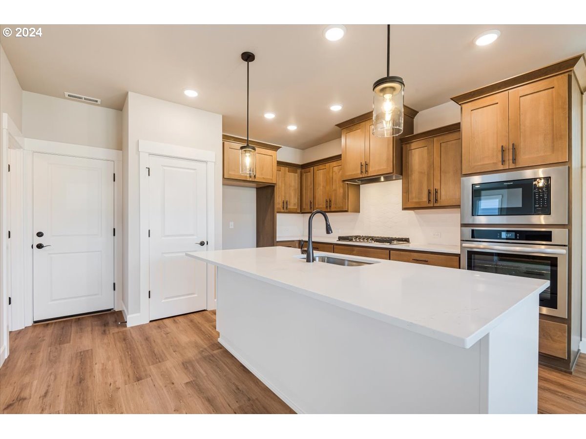 18050 Southwest Barrows Road Beaverton, OR 97007 - Photo 10 of 45 a large kitchen with stainless steel appliances kitchen island granite countertop a sink a stove and a refrigerator