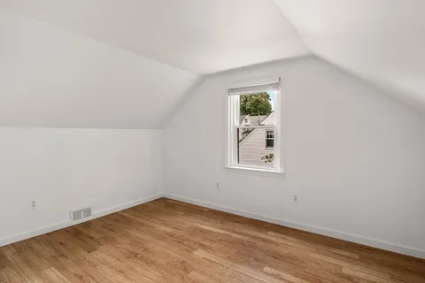 an empty room with wooden floor and window
