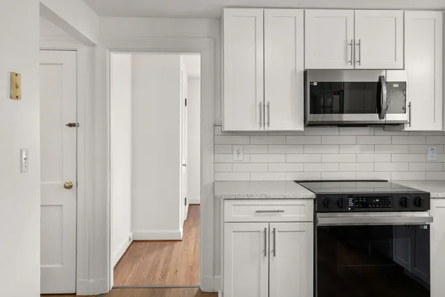 a kitchen with white cabinets and stainless steel appliances