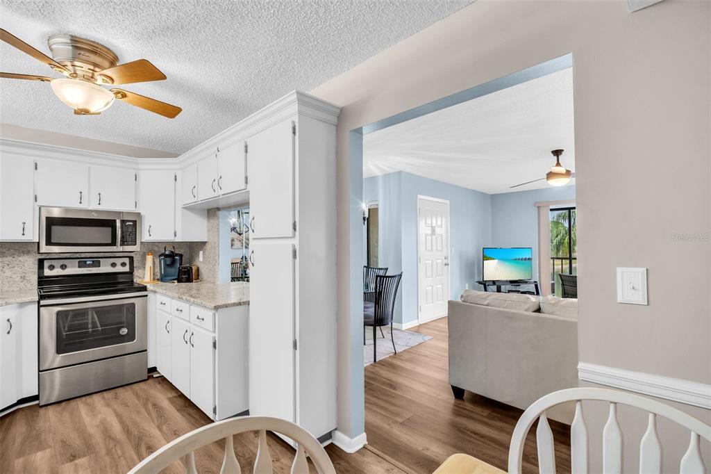 2523 Pine Ridge Way South, Unit C2 Palm Harbor, FL 34684 - Photo 12 of 29 a kitchen with stainless steel appliances a stove a refrigerator a sink a stove with white cabinets and wooden floor