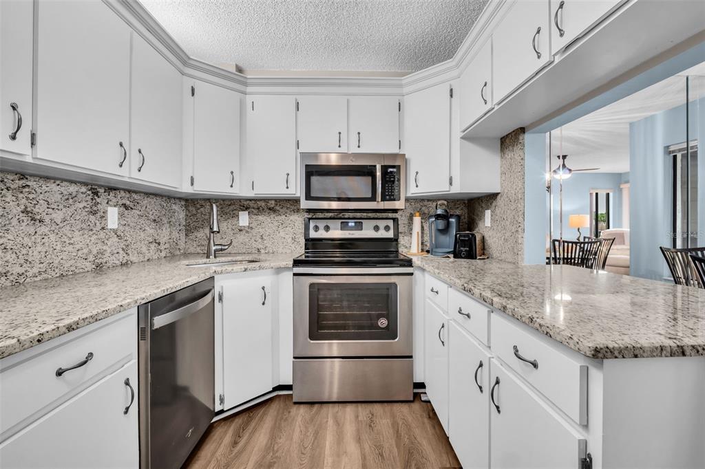 2523 Pine Ridge Way South, Unit C2 Palm Harbor, FL 34684 - Photo 13 of 29 a kitchen with granite countertop a stove sink and cabinets