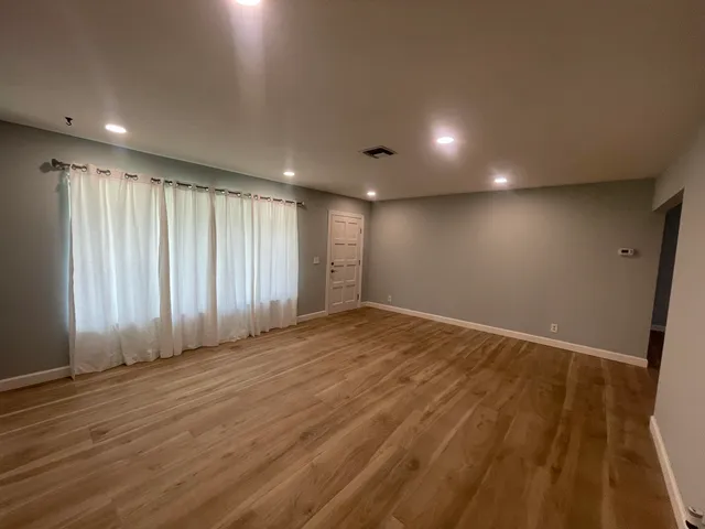 an empty room with wooden floor and windows